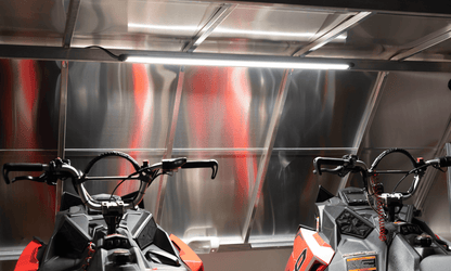 Kingpin v-Series 40" light bar illuminating two Polaris mountain snowmobiles inside enclosed aluminum trailer. 